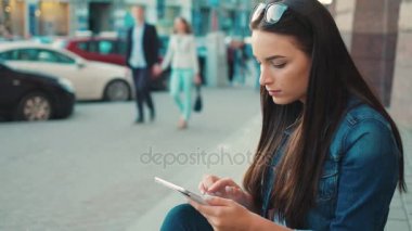 Merdivenlerde şehir sokak üzerinde otururken tablet aygıtı kullanan güzel kadın. Okuma, dokunmatik ekran dokunarak, tarassut video kadın. Yakın çekim