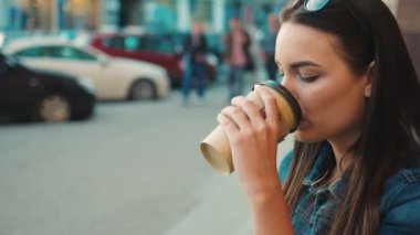 Şehrin sokak gitmek için çekici kadın kahve içme. Portre vurdu. Belgili tanımlık merdiven üstünde oturup, kahve içme ve kameraya bakarak kadın. Yakın çekim