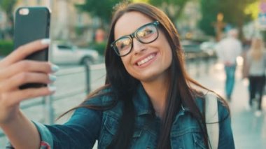 Selfies smartphone üzerinde şehrin sokak alarak genç güzel kadın. Akıllı telefon kameraya poz kadın gülümsüyor. Yakın çekim
