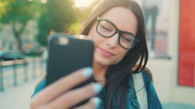 Selfies smartphone üzerinde şehrin sokak alarak genç çekici kadın kadar kapatın. Akıllı telefon kameraya poz kadın gülümseyerek.