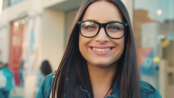 Ritratto di donna vicino alla strada della città. Donna attraente con gli occhiali e guardando la fotocamera e sorridendo . — Video Stock