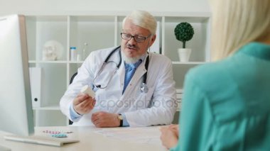 Bayan hasta ile uyuşturucu hakkında konuşurken onun ofisinde oturan sakallı erkek doktor bardaklarda beyaz orta yaşlı.