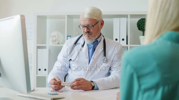 Médico masculino caucásico sentado en su offise, hablando de drogas y dando drogas a una paciente joven. De interior . — Vídeos de Stock