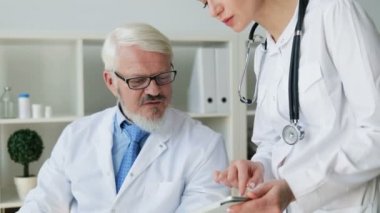 Beyaz genç güzel kadın doktor ve orta tablet kullanarak gözlüklü erkek doktor yaşlı. Kapalı.