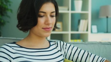 Kanepede oturan ve laptop ile çalışma güzel esmer kadın portresi kapatın. Kameraya bakarak ve gülümseyen kadın. Portre vurdu