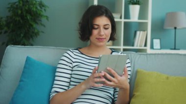 Tablet bilgisayar ve esneme duygu ile çalışan güzel genç kadın yorgun. Evde kanepede oturan kadın