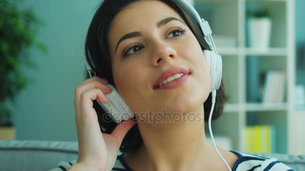 Close up beautiful young woman listening to music in big white headphones. — Stock Video