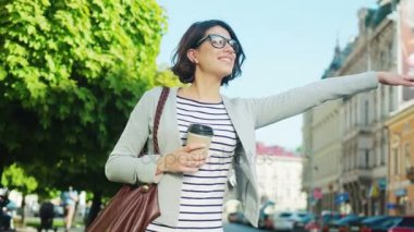 Bir taksi durdurmak için mutlu genç kadın taksi şehrin sokak. Bir araba yakalamak için kadın el sallayarak