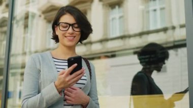 Çekici esmer kadın sokakta büyük pencere yakın cep telefonuyla konuşuyor. Açık havada.