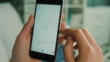 New York - 10 Şubat 2017: Akıllı telefon App Store uygulama kullanarak ve ilginç program oturma odasında arama kadın eller. Yakın çekim.