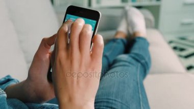 New York - 10 Şubat 2017: Kadın el giysi online mağazasında Koç evde oturma odasında yatan süre araştırıcı için akıllı telefonda Amazon kullanarak. Yakın çekim.