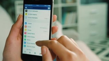 New York - 10 Şubat 2017: kadın burada acount akıllı telefon kanepede yatan süre ayarlama Facebook tarama. Atış kapatın.