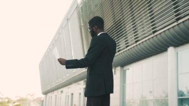 Belgeler, kağıtları tutan cep telefonda konuşurken genç çekici Afrikalı-Amerikalı iş adamı. İş adamı kızgın ve tatminsiz arıyorum. Dışında yakın ofis binası