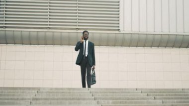 Merdivenlerde, yürürken cep telefonda konuşurken çekici genç Afro-Amerikalı iş adamı adımlar office merkezine yakın bina.