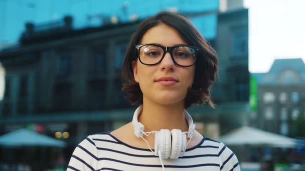 Ritratto volto di bella donna con le cuffie sulla strada della città. Una donna sorridente. Da vicino. — Video Stock