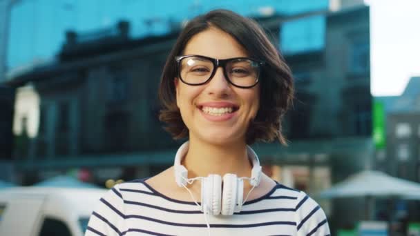 Πρόσωπο πορτρέτο του ελκυστική γυναίκα με ακουστικά σε δρόμο της πόλης. Γυναίκα, που χαμογελά. Κοντινό πλάνο — Αρχείο Βίντεο