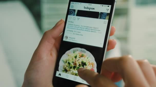 New York - 10 mars 2017: Kvinna med Instagram-appen på smart phone, rullning foto i instagram ansökan. Närbild. Inomhus skott. — Stockvideo