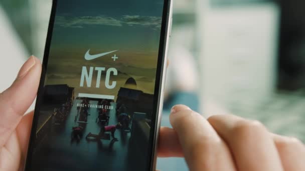 New York - 10 martie 2017: Mâinile femeii se pregătesc de alergare, pornesc aplicația Nike run pe telefonul inteligent în timp ce stau pe antrenor în camera de zi de acasă. Close up . — Videoclip de stoc