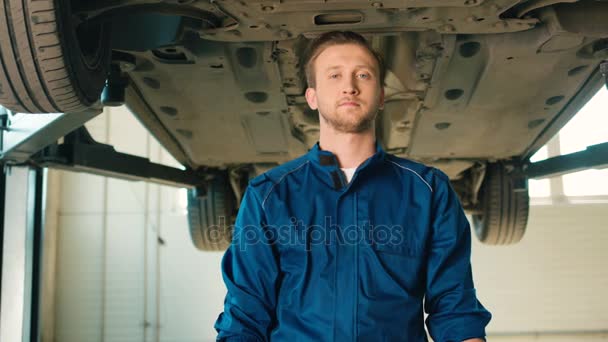 Πορτραίτο του Καυκάσου auto μηχανικός σε μπλε στολή με τα μαλλιά ρους κρατώντας ένα γαλλικό κλειδί στο χέρι και να συνθέτει τα χέρια σε φόντο βεντούζες. Εσωτερική. — Αρχείο Βίντεο