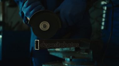 Otomatik mekanik autoservice mavi üniformalı ayakta ve demir blok kesme. Kapalı. Yakın çekim.