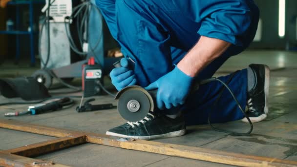 Automechaniker auf Autoservice-Hintergrund in blauer Uniform und Helm beim Sägen des Holzblocks. Innenräume. — Stockvideo