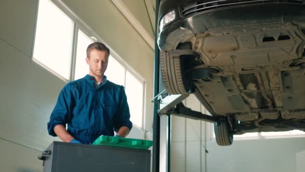 Autoservice içinde ayakta ve otomatik araçları ile ilgilenen genç ciddi beyaz otomatik mekanik adam. Kapalı. — Stok video