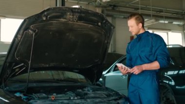 Autoservice tablet için araba açıklama başlık altında mekanizmaları durumunu kullanarak ciddi beyaz otomatik mekanik adam. Kapalı.