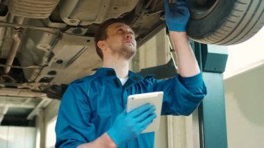 Kafkas Oto tamirci adam arabanın alt mekanizmaları durumunu açıklaması için tablet kullanarak autoservice yoğunlaştı. Kapalı.