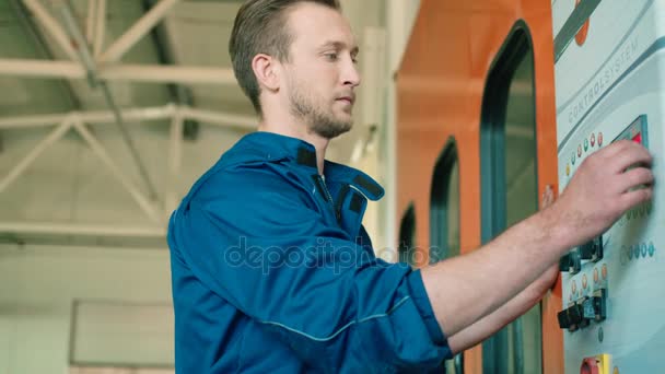 Grave caucásico joven mecánico de automóviles en uniforme azul y cabello rosado utilizando el panel de control del coche en autoservicio. De interior . — Vídeos de Stock