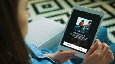 New York - 15 Mayıs 2017: kanepede otururken tablet aygıtı kullanan kadın. Kadın el beyaz tablete app çalıştıracağınız nike açın. Nike eğitim kulübü. Yakın çekim. Omuz atış üzerinde