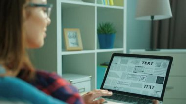 New York - 15 Mayıs 2017: oturma odasında kanepede otururken dizüstü bilgisayar kullanan genç kadın. Tipik dizüstü klavye üzerinde eller kadın. Metin harfler. arka yan görünüm