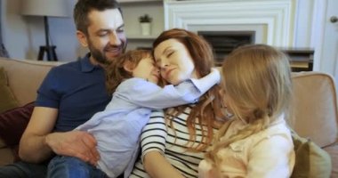 Mutlu genç aile kanepede oturan. Mutlu bir aile evde birlikte vakit. Sarılma ve öpüşme anne oğlu. Annesi, babası, oğlu, kızı