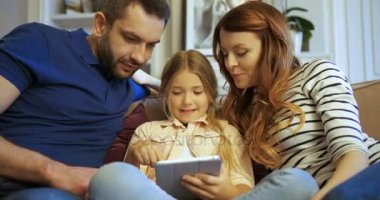 Anne, baba ve kızı kullanarak tablet, oyun oynamak ve eğlenmek. Evde birlikte vakit aile.