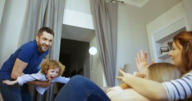 Mutlu bir aile evde birlikte vakit. Oğluyla anne kucaklama kız oynama baba. Uçak poz. Annesi, babası, oğlu, kızı