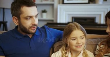 Anne, baba ve kızı evde birlikte vakit. Mutlu aile oturma odasında kanepede otururken konuşuyor