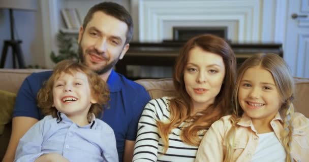 Portrét mladé rodina sedí na gauči. Šťastná rodina tráví čas spolu doma. Matka, otec, syn, Dcera — Stock video