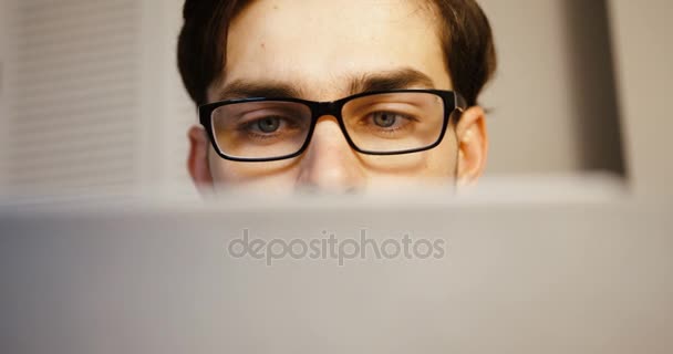 Atractivo joven hombre de negocios que trabaja en el ordenador portátil en la oficina. De cerca. . — Vídeos de Stock