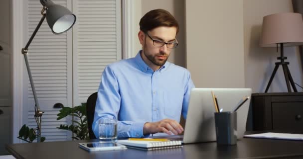 Tânărul tastează pe laptop. Un om serios care lucrează la laptop la birou. Birou fundal . — Videoclip de stoc