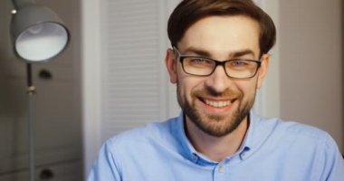 Possing office arka plan üzerinde kamera için genç adam. Kameraya gülümseyen çekici iş adamı. Yakın çekim.