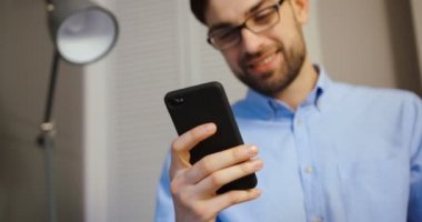 Akıllı telefon yazarak genç iş adamı. Çekici mutlu adam workinh ofiste.