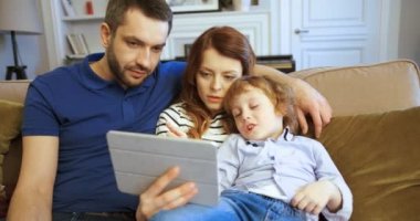 Anne, baba ve oğul film izlerken tablet, kullanma. Dokunmatik ekran tablet cihaz dokunarak ve kaydırma. Evde birlikte vakit aile. Mutlu bir aile