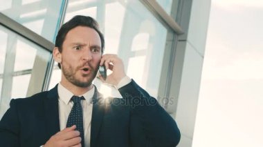 Genç işadamı öfkeli duyguları ile cep telefonuyla konuşurken kapatın. Bağırarak ve üzgün bir adam. Açık havada ofis Merkezi