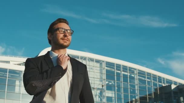 Heureux homme d'affaires attrayant marchant près du bâtiment du centre de bureaux, souriant et levant les mains en position heureuse . — Video