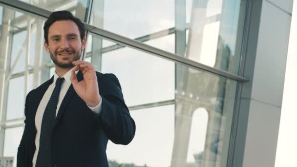 Όμορφος επιχειρηματίας δείχνει αστείο συναισθήματα ενώ στέκεται σε εξωτερικούς χώρους κοντά σε μεγάλα παράθυρα. Κοντινό πλάνο — Αρχείο Βίντεο