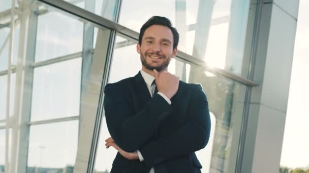 Portrait of attractive stylish businessman looking straight at the camera while standing near office center building outdoors. Close up — Stock Video