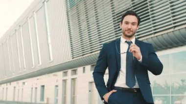 Gözlükleri çıkar alarak ve kameraya bakarak genç çekici işadamı portresi. Gülümseyen ve yapım adam Yaşasın. yakın çekim