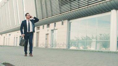 Cep telefonuyla konuşurken ve mutlu etmek genç çekici işadamı taşır. Çok güzel bir haber duydum adam ve açık havada dans ofis bina merkezi