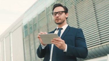 Tablet bilgisayar cihaz üzerinde iyi haber okuma genç çekici businessamn. Şehirde bina ofis Merkezi yakınındaki dijital tablet aygıtı kullanan adam. Yakın çekim