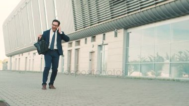 Beyaz genç işadamı cep telefonda konuşurken. İyi haber işitme ve mutlu bir şekilde dans ouside ofis iş adamı. Açık havada. Komik dans