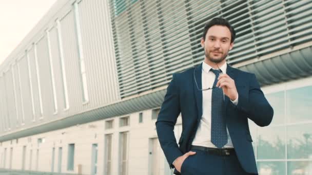 Retrato de un joven empresario atractivo quitándose las gafas y mirando a la cámara. Hombre sonriendo y haciendo pulgares hacia arriba. de cerca — Vídeos de Stock